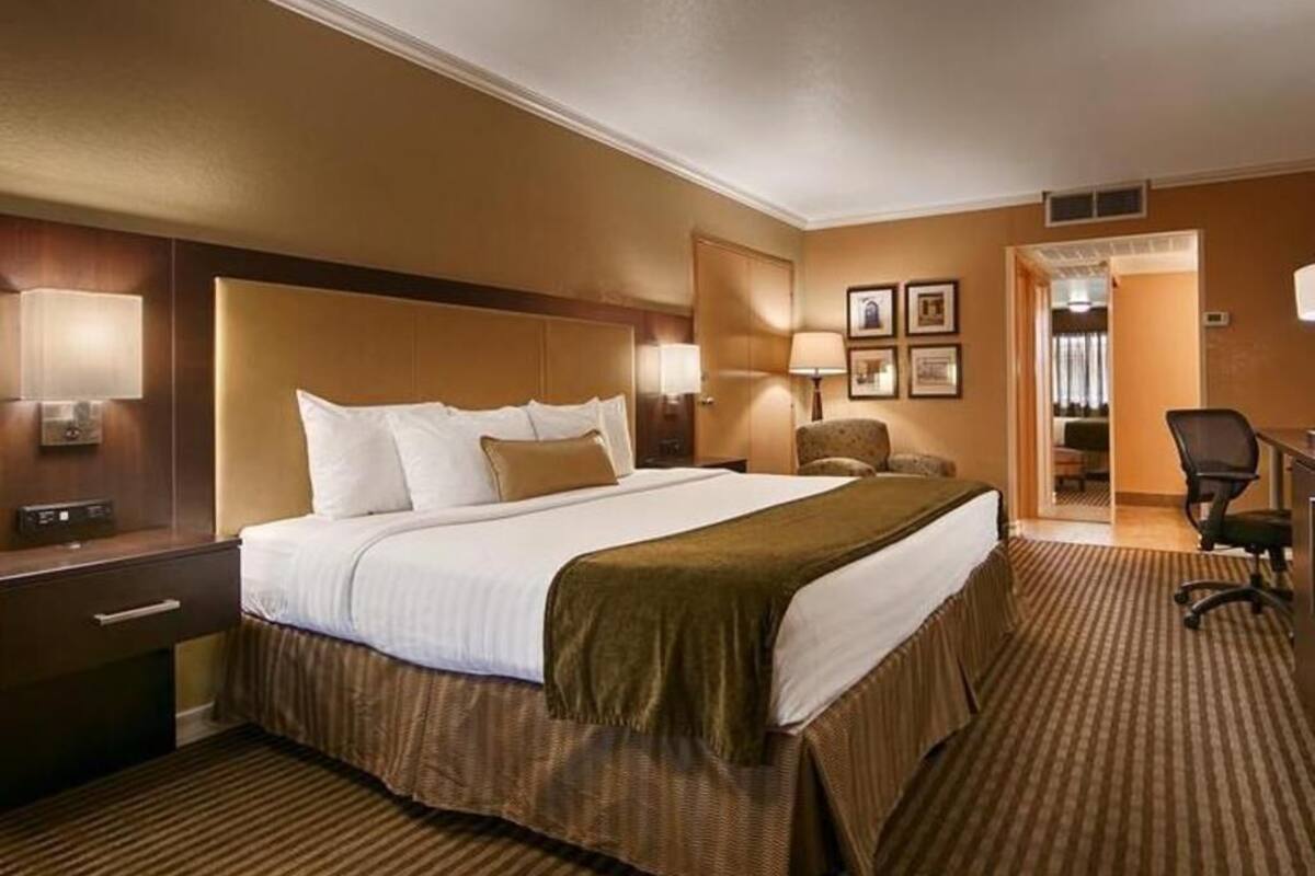A hotel room with a large bed, bedside tables, a desk, and a chair.