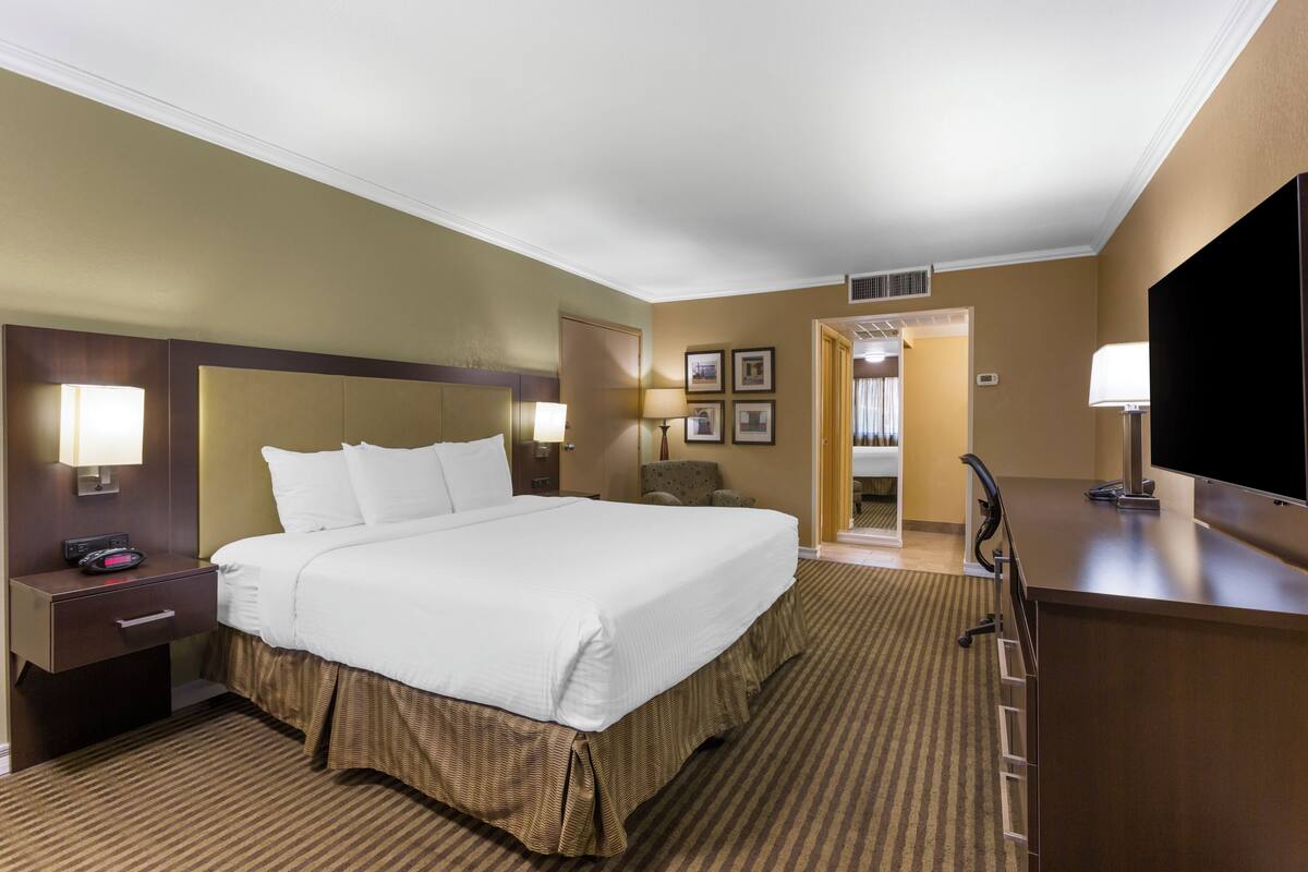 A hotel room with a large bed, bedside tables with lamps, a desk with a chair, and a television.