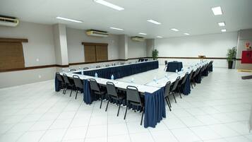 Uma sala de conferências com uma mesa comprida, cadeiras e garrafas de água.