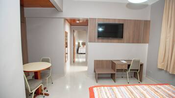 Une chambre d’hôtel comprenant un lit, un bureau, une chaise, un téléviseur fixé au mur et une petite table avec une chaise.