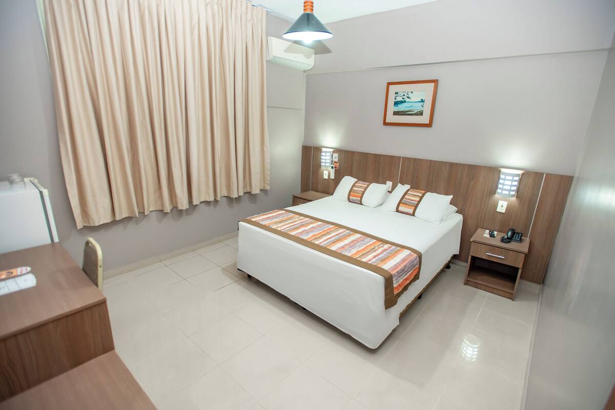 A hotel room with a bed, bedside tables, a desk, and a chair.