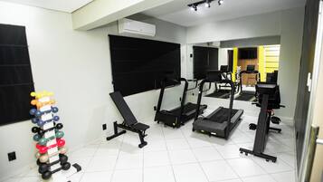 A gym with various exercise equipment including treadmills, a bench, and a dumbbell rack.