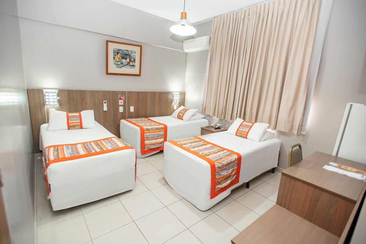 A hotel room with two single beds, a desk, and a chair.