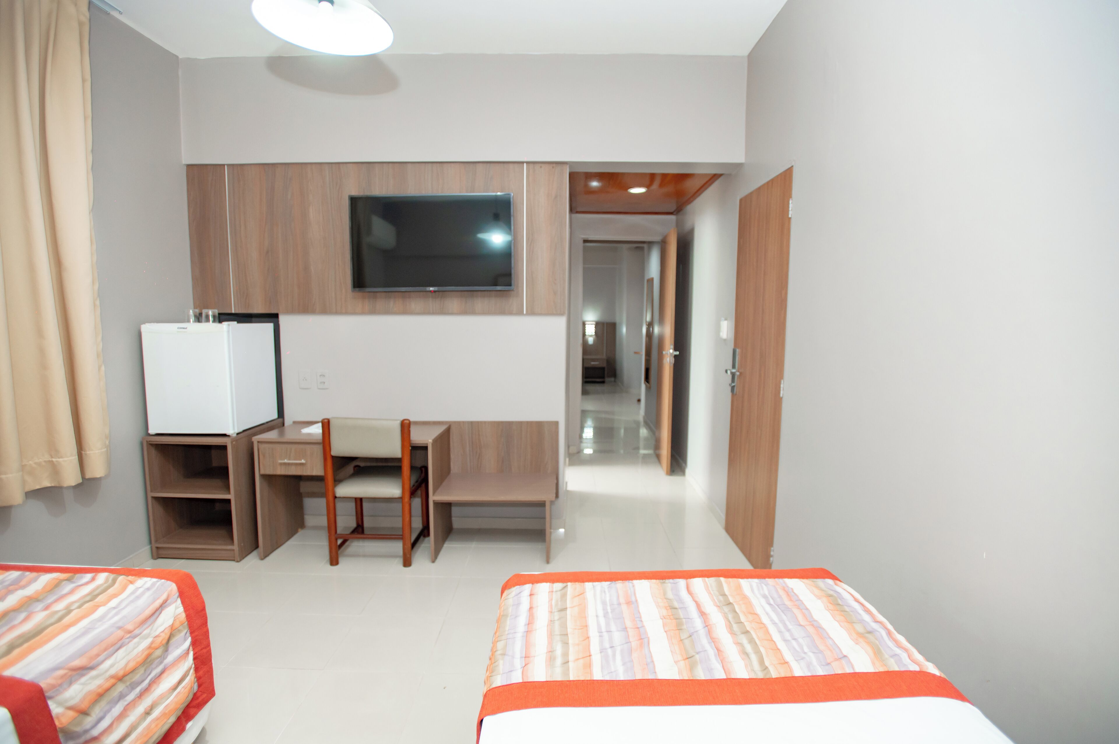 Habitación de hotel con dos camas, un escritorio, televisión y armario.