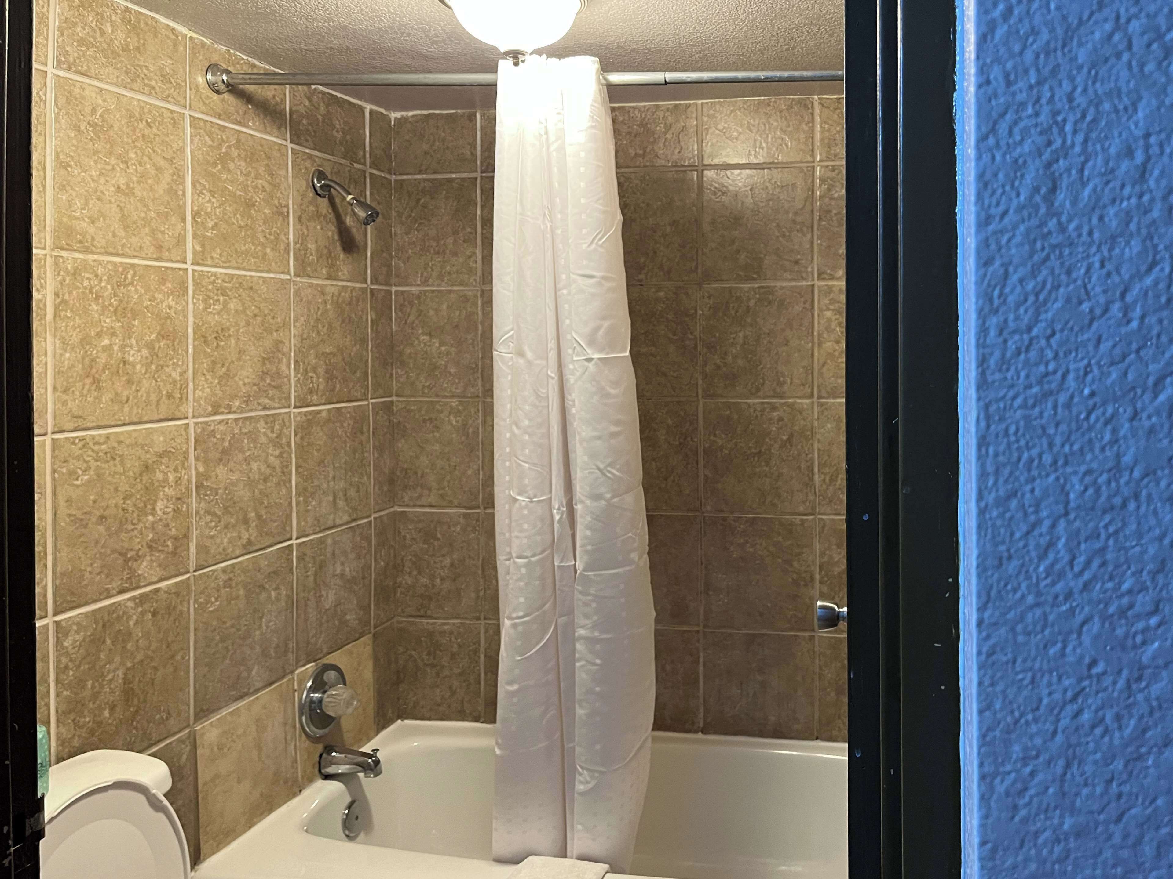 A bathroom with a bathtub, shower, and toilet.