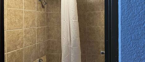 A bathroom with a bathtub, shower, and toilet.