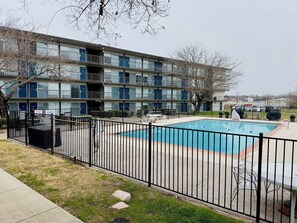 Un edificio de varios pisos con piscina rodeada por una cerca de metal negro.