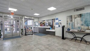 A reception area with a glass door entrance, a counter with a computer, and a wall with informational posters.