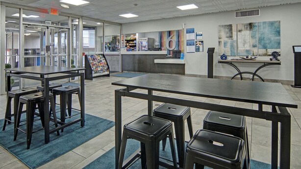 A modern library with tables, stools, and bookshelves.