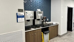 A modern coffee station with two ice dispensers, a coffee machine, and a trash bin.