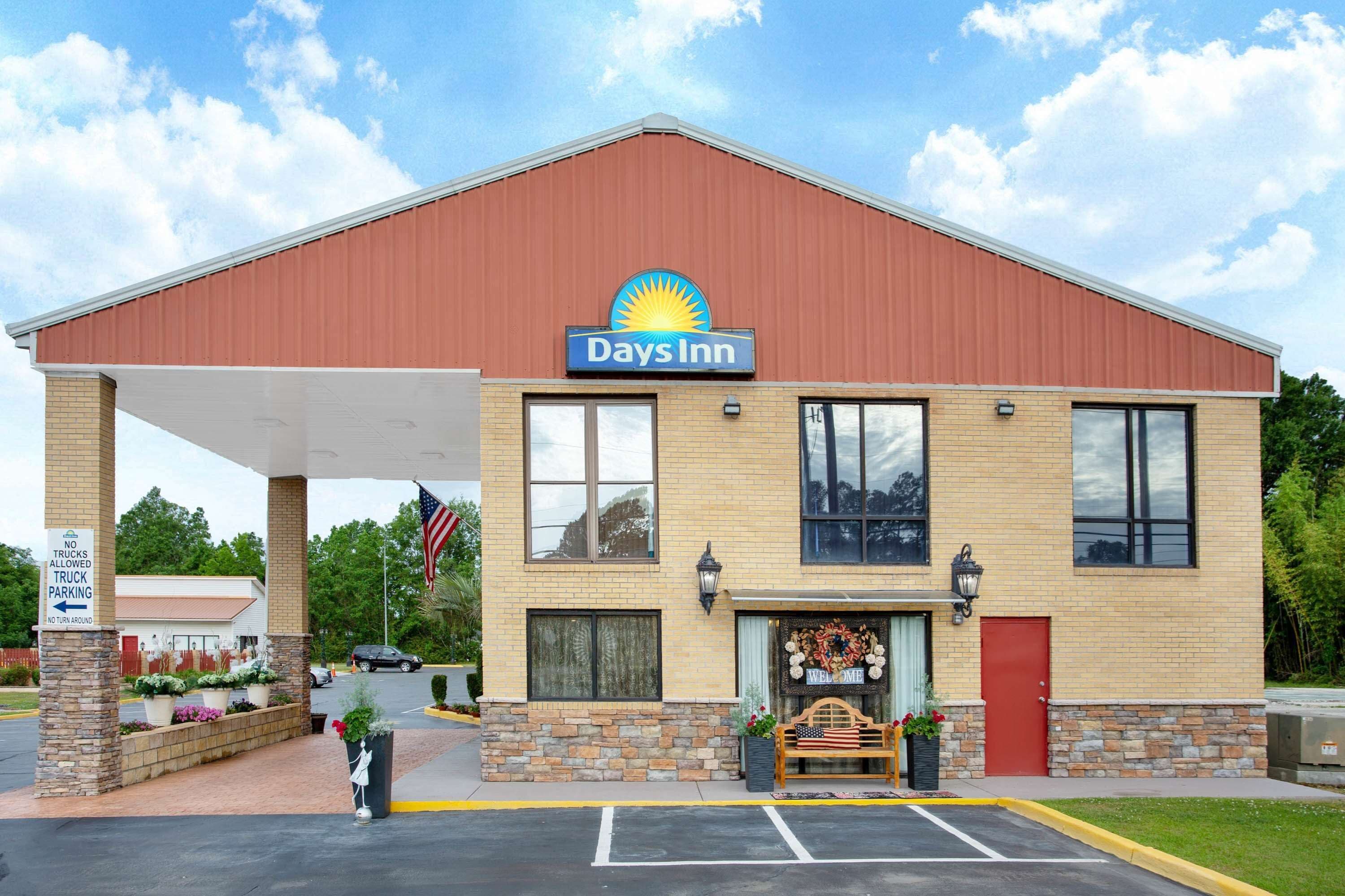 Un Days Inn con techo rojo, fachada de ladrillo y un cartel de 'Welcome'.