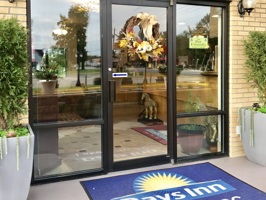 A hotel entrance with a glass door, a welcome mat, and a sign for Days Inn Lake City, SC.
