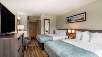 A hotel room with two beds, a desk with a TV, a chair, and a painting on the wall.