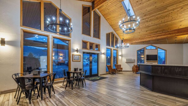 A spacious room with a high ceiling, large windows, and a wooden floor.