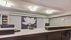 A reception desk with a Planar monitor, a large lotus flower mural, and a clock on the wall. - Travelodge by Wyndham Houston Cy-Fair (Houston)