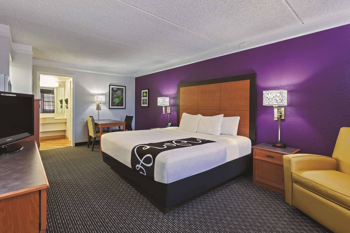Una habitación de hotel con una cama grande, un escritorio, una silla y un televisor.