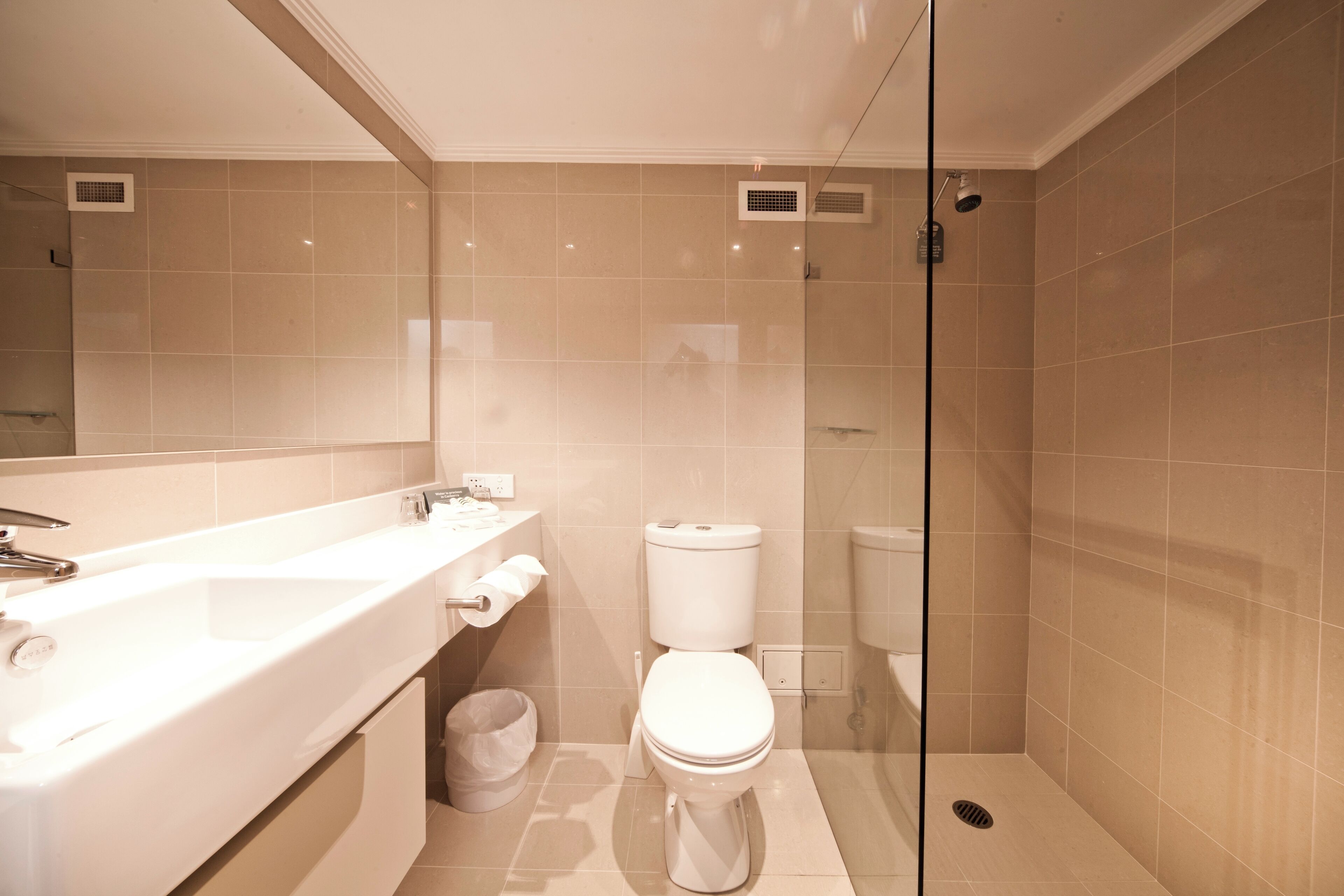 Un baño moderno con cabina de ducha de vidrio, un lavabo blanco y un inodoro.