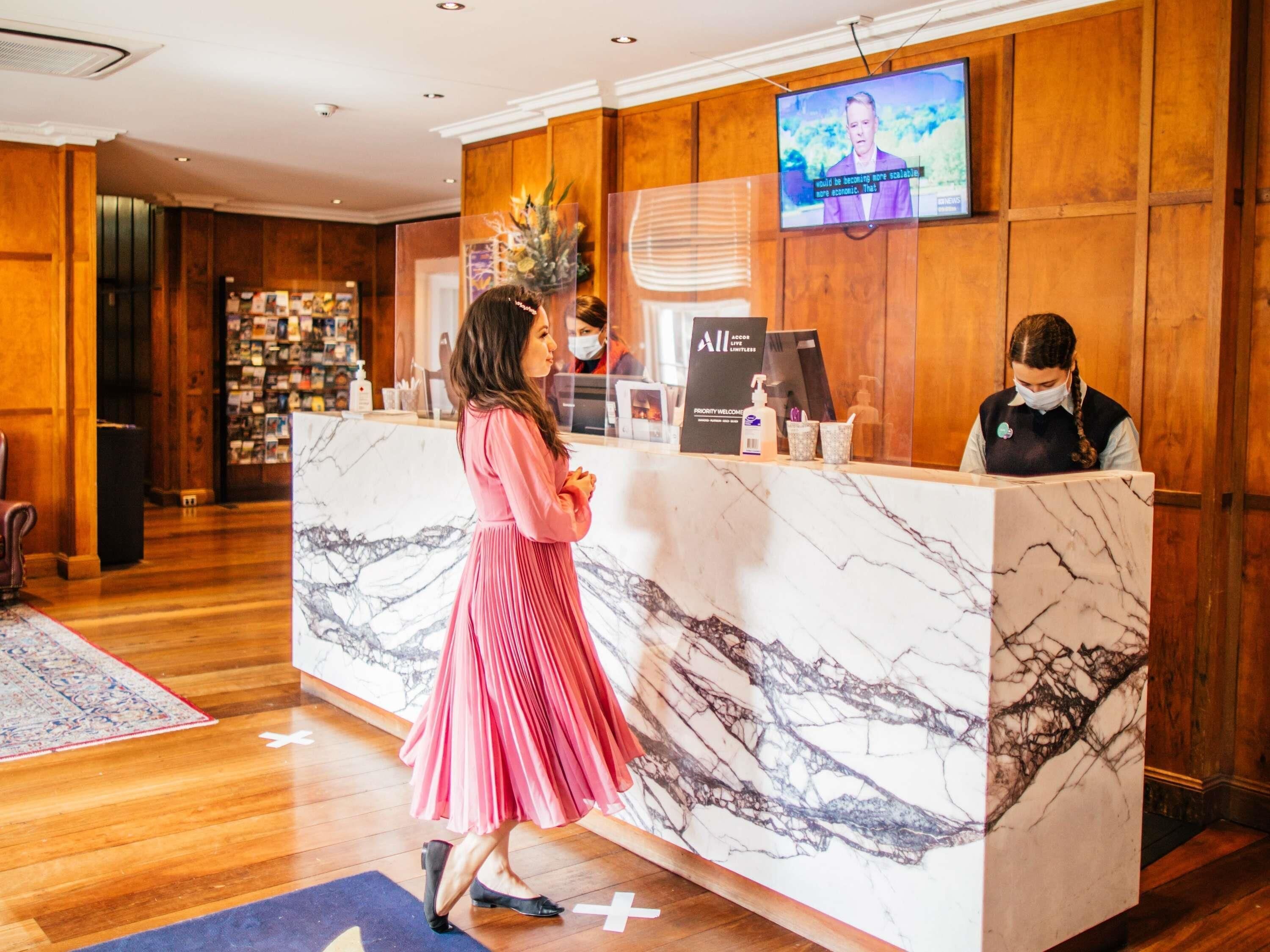 A reception desk with a marble top, a television screen, and a 'Priority Welcome' sign.
