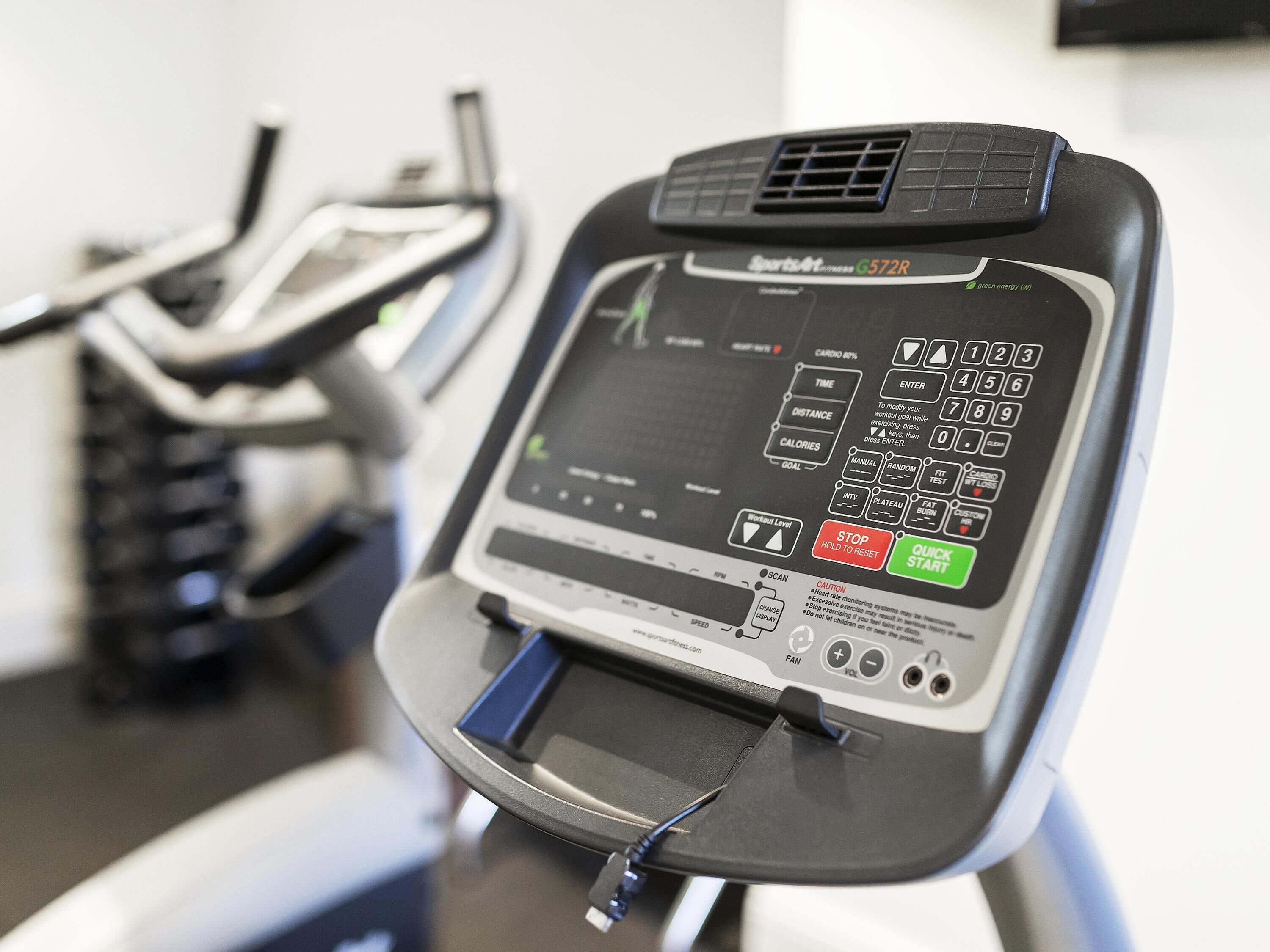 Een stilstaande hometrainer met een digitaal display, bedieningspaneel en een kleine ventilator.