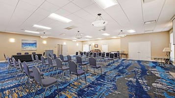 A conference room with rows of chairs, a carpeted floor, and ceiling lights.