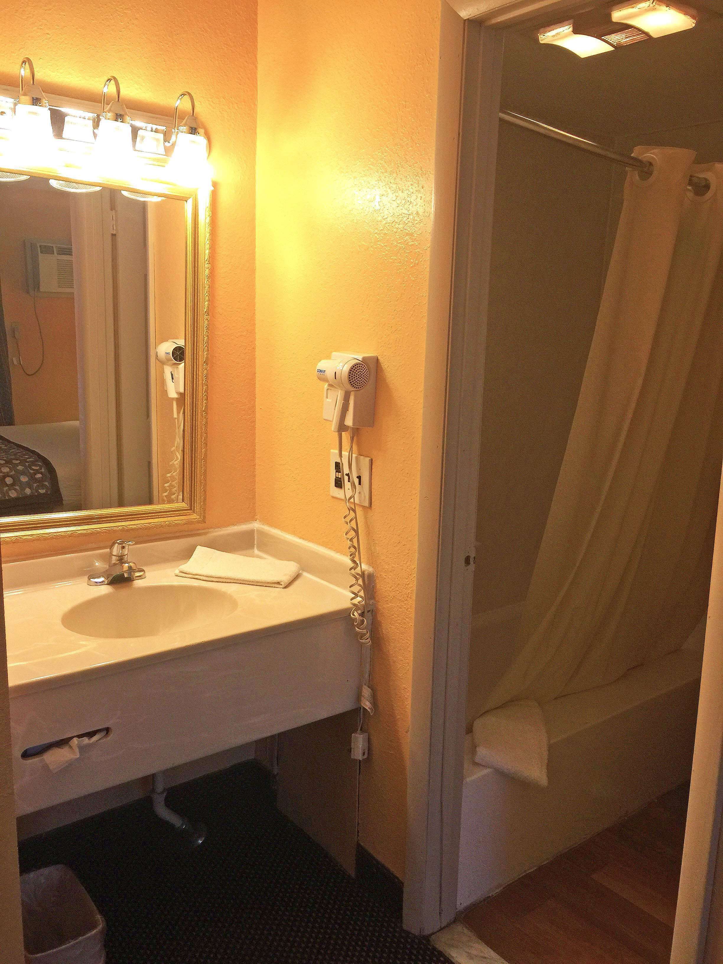 A bathroom with a sink, mirror, and a hairdryer mounted on the wall.