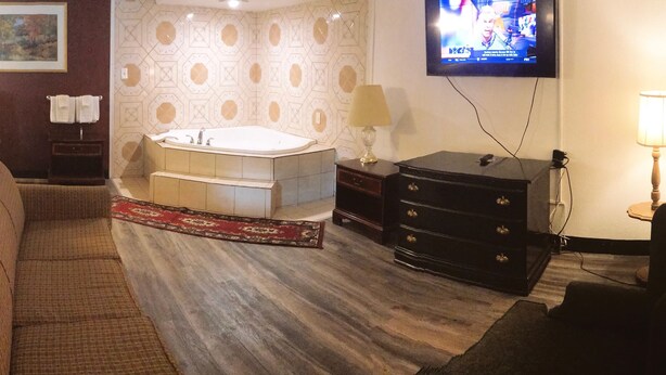 A hotel room with a bed, a desk, a sofa, a bathroom with a bathtub, and a TV on the wall. - Americas Best Value Inn Pottstown (Pottstown)