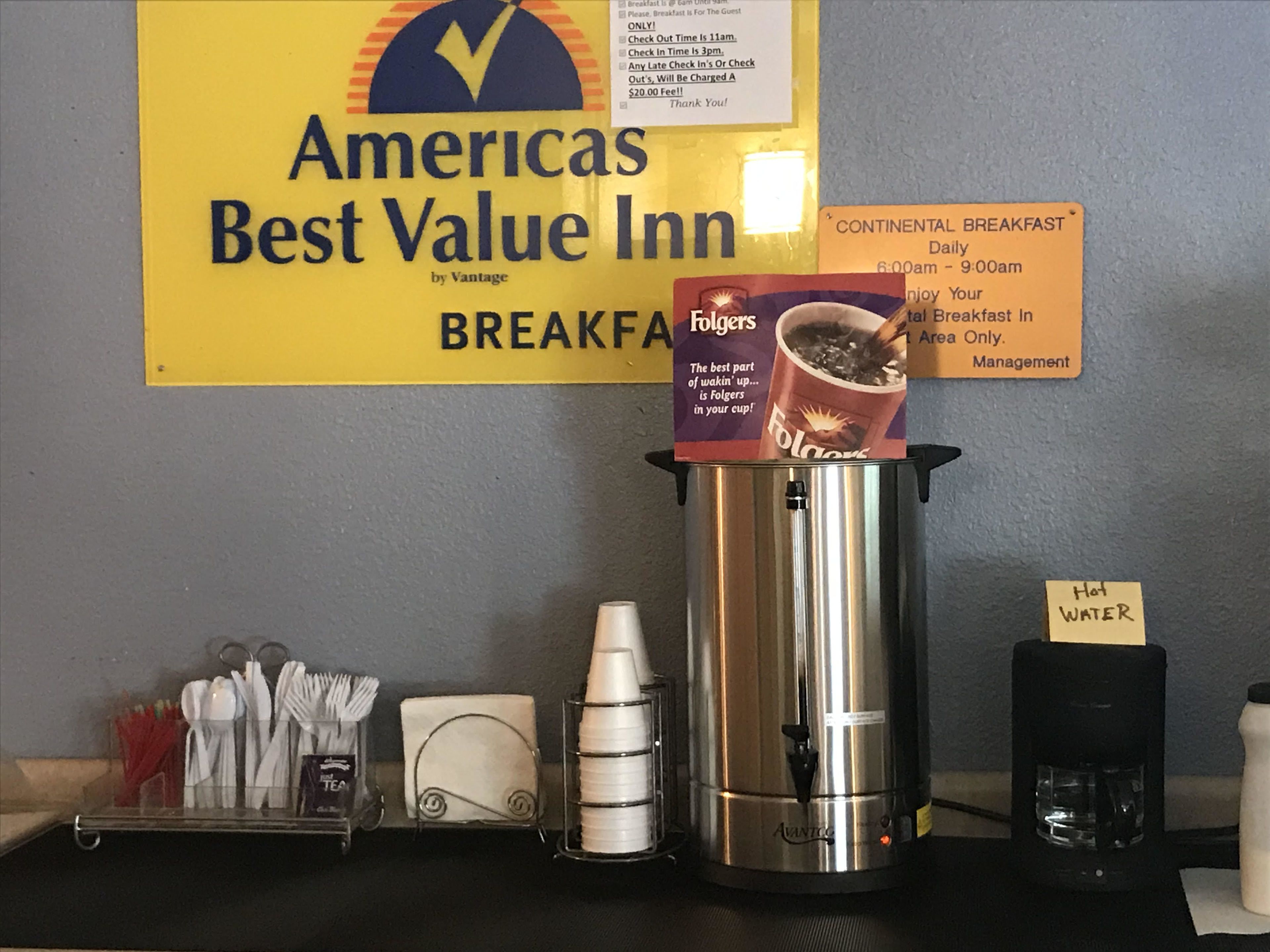 A breakfast station at the Americas Best Value Inn with a coffee maker, cups, and utensils.