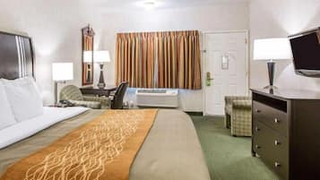 A hotel room with a bed, a desk, a chair, a dresser, and a television.