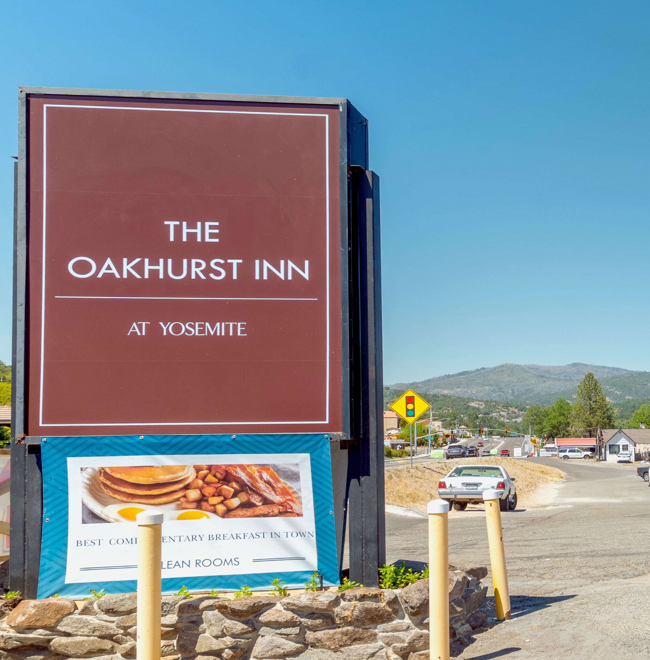 Een bord voor The Oakhurst Inn bij Yosemite, met een advertentie voor ontbijt.