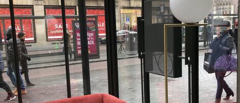 Un interior moderno con un sofá rojo, una mesita y un ventanal con vistas a la calle.