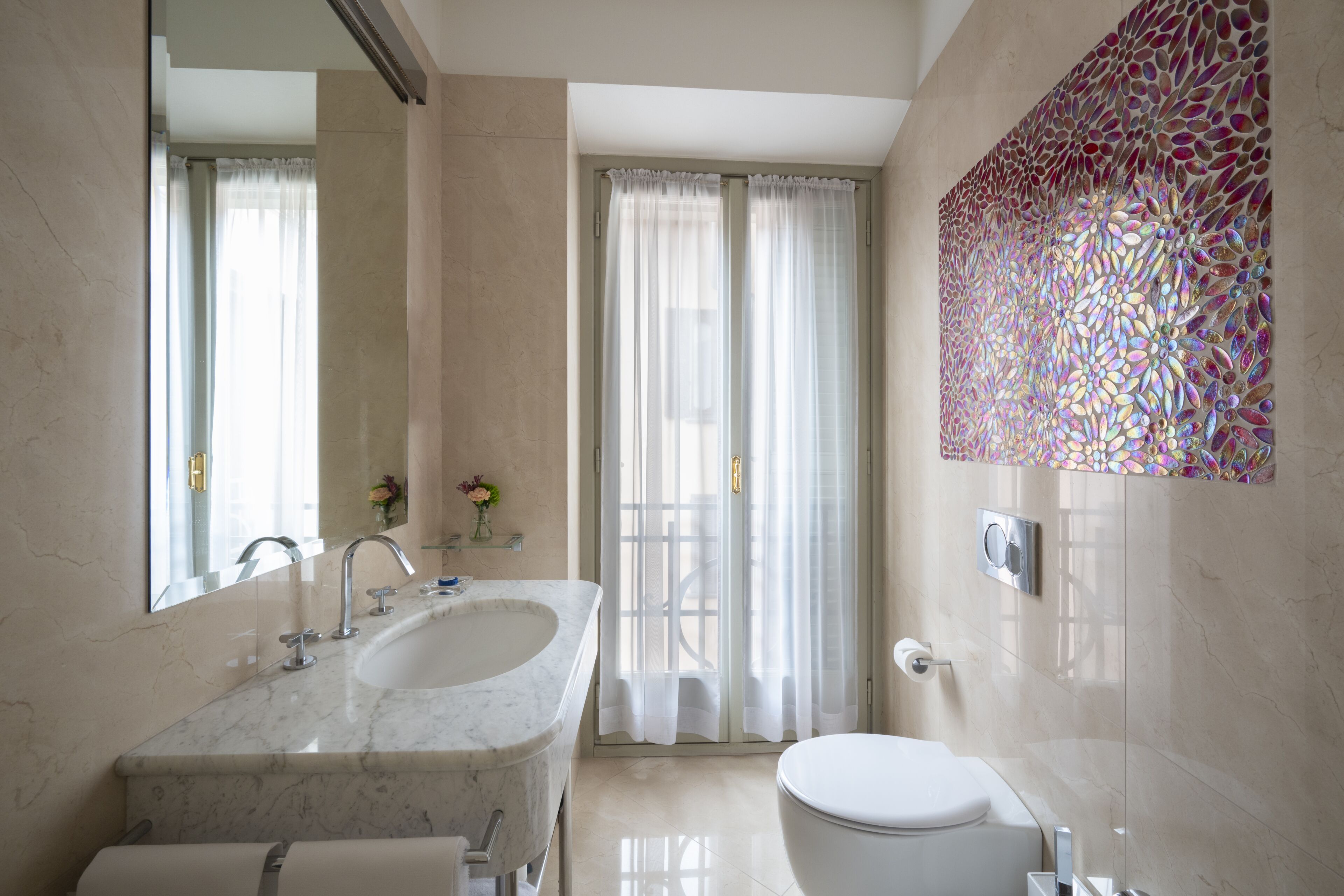 Un baño moderno con lavamanos de mármol, inodoro y zona de ducha.