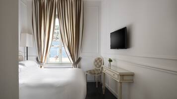 Een hotelkamer met een bed, een bureau, een stoel, een televisie en een raam met gordijnen.