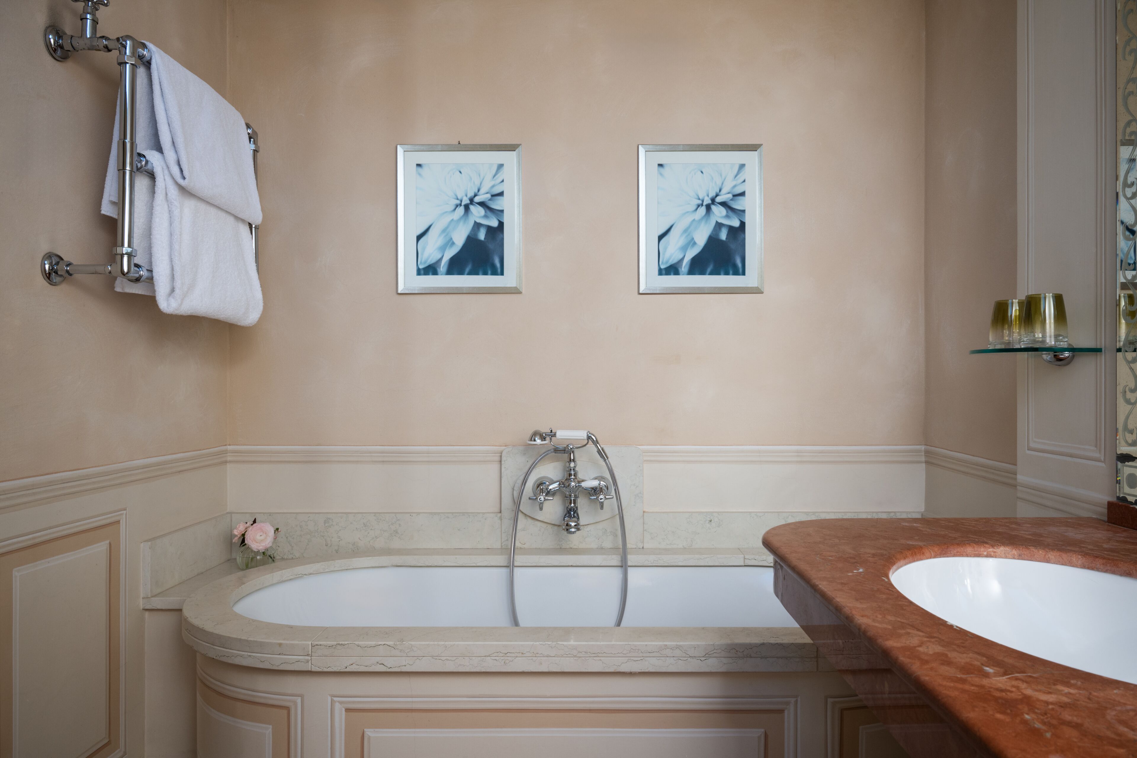 A bathroom with a bathtub, a shower, a marble countertop, and two framed pictures on the wall.