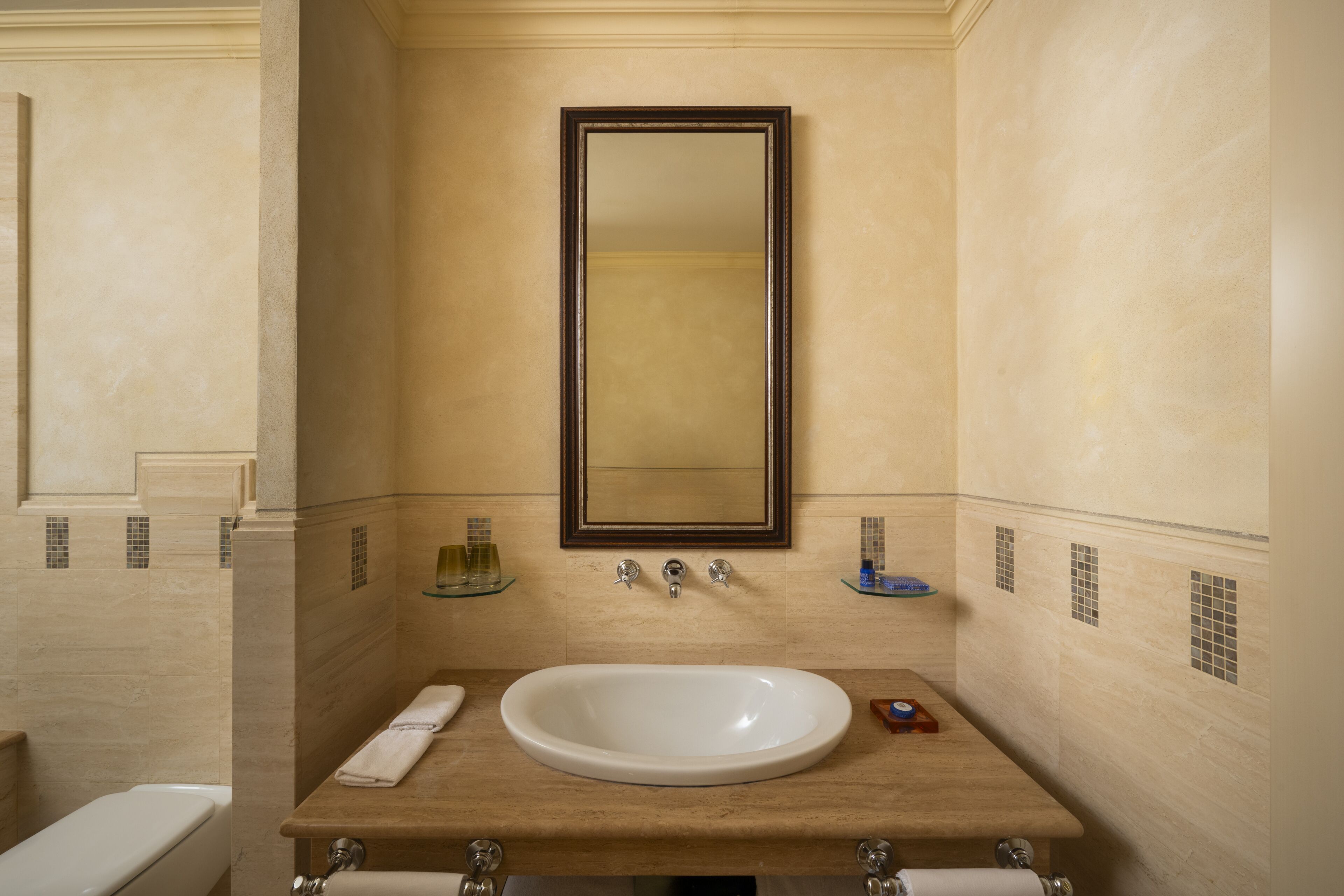 Un bagno con lavandino bianco, specchio e portasciugamani.