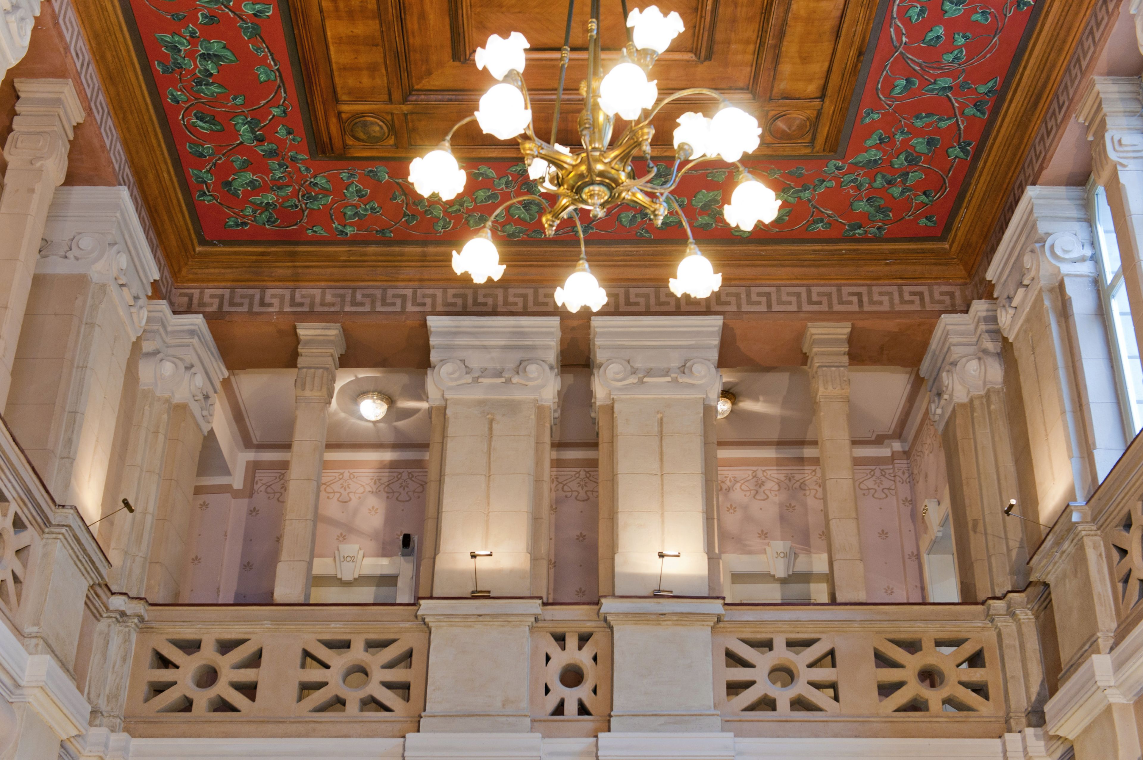 Un salón imponente con columnas ornamentadas, un techo decorativo y una araña.