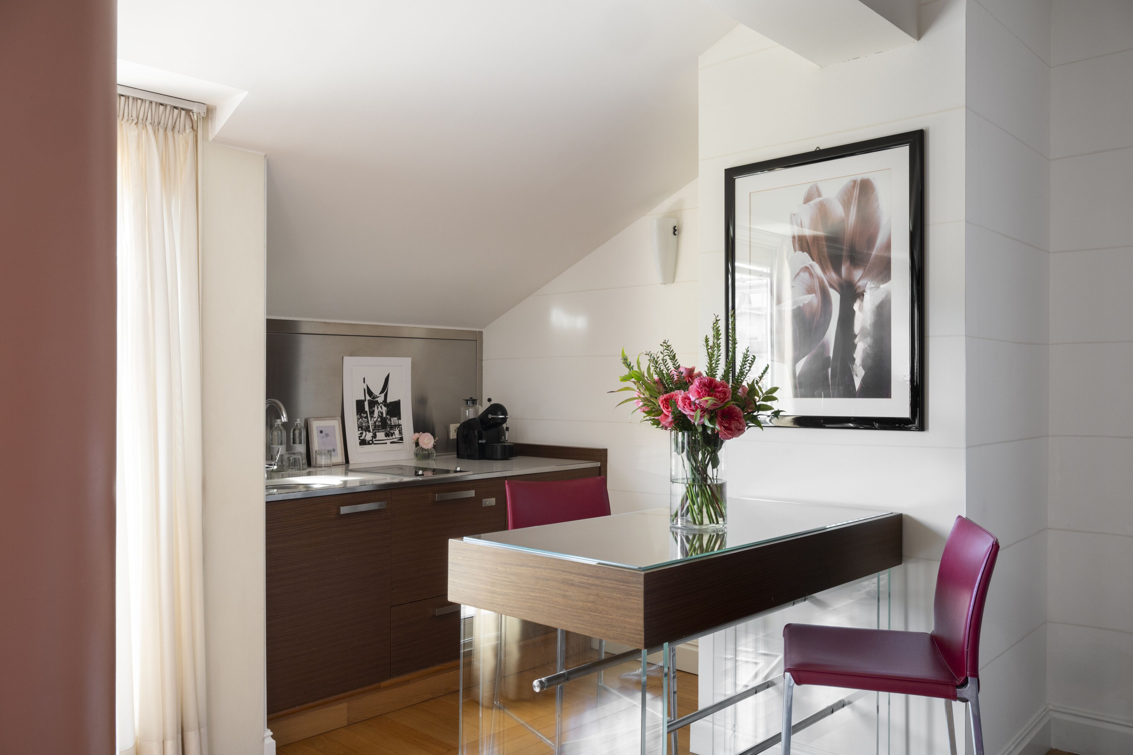 Une cuisine moderne avec un coin repas, un vase rempli de fleurs et un tableau encadré au mur.