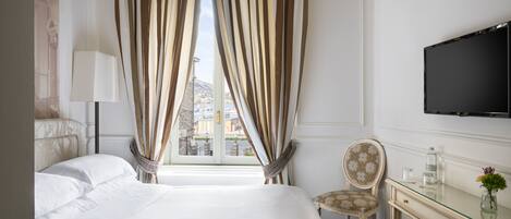 A hotel room with a bed, a desk, a chair, a TV, and a window with curtains.