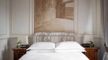 A hotel room with a large bed, two bedside tables, a nightstand, a wall-mounted lamp, and a view through a window.