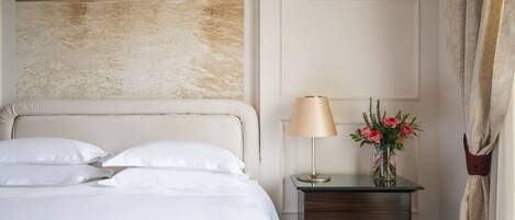 Una habitación de hotel con una cama, una mesita de noche con una lámpara y flores, una pared con un cuadro y una cortina.
