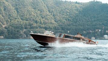 A speedboat on a lake with a forested hillside in the background.