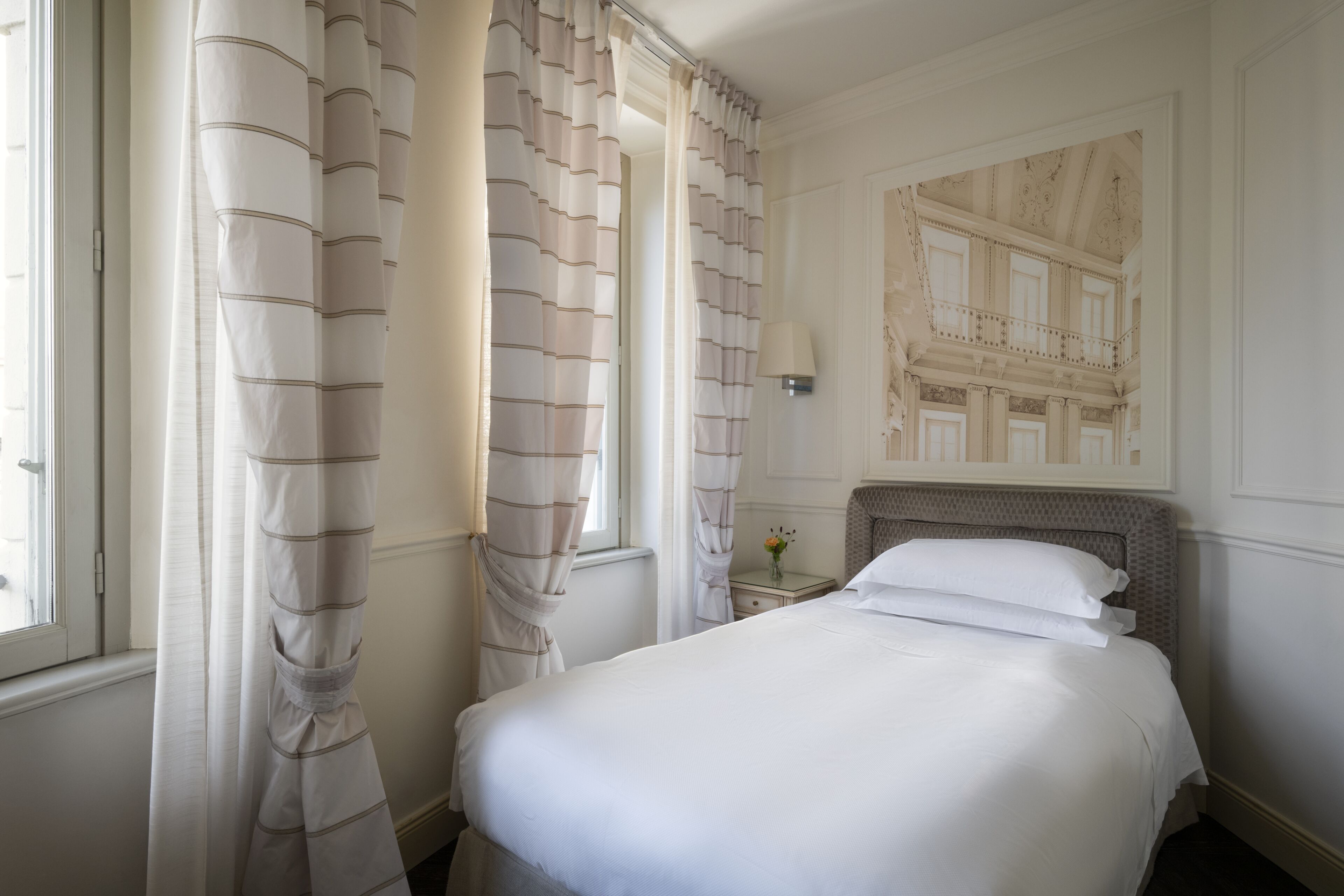 Una cama bien hecha en una habitación de hotel con vista a un edificio a través de una ventana.