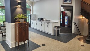 A hotel lobby with a reception desk, a vending machine, a trash bin, and a sign indicating the hotel name and amenities. - The Hotel Ojibway, Trademark Collection by Wyndham (Sault Ste. Marie)