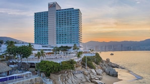 Hotel alto com área de piscina, acesso à praia e vista para o oceano.