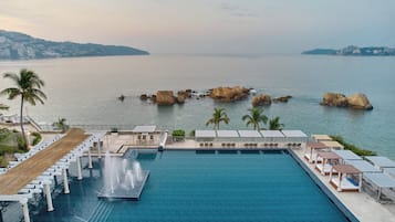 Una piscina al aire libre, camas de piscina con cargo, sombrillas