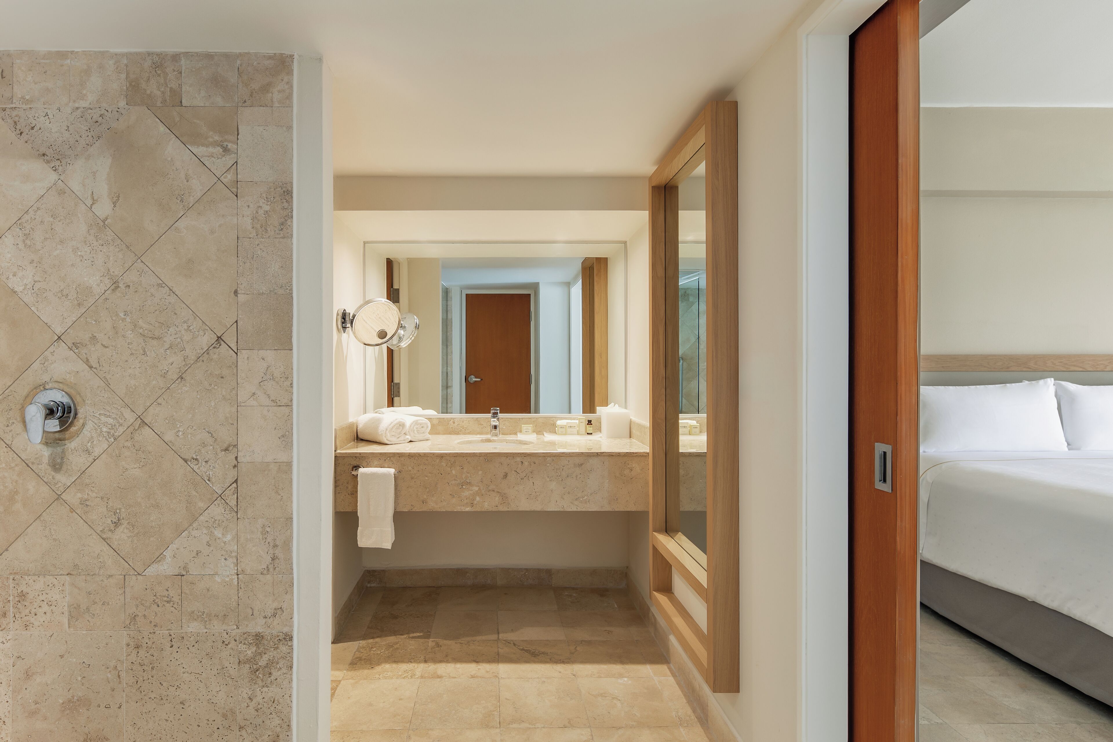A hotel bathroom with a shower, sink, and mirror.