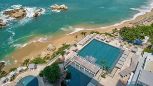 Um resort com uma grande piscina, acesso à praia e vista para o oceano.