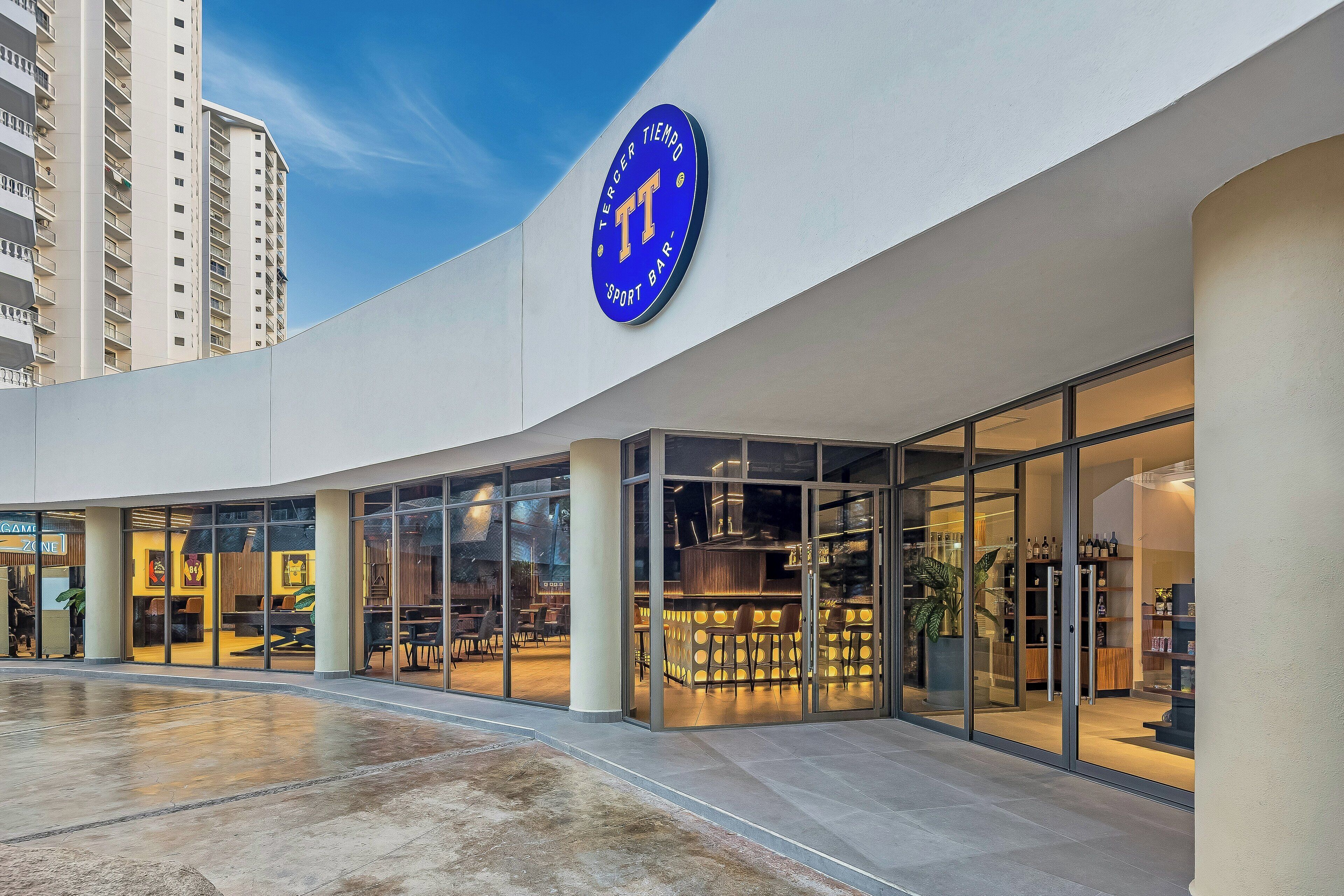 Un bâtiment moderne avec une grande enseigne bleue sur laquelle on peut lire : « TERCER TIEMPO SPORT BAR ».