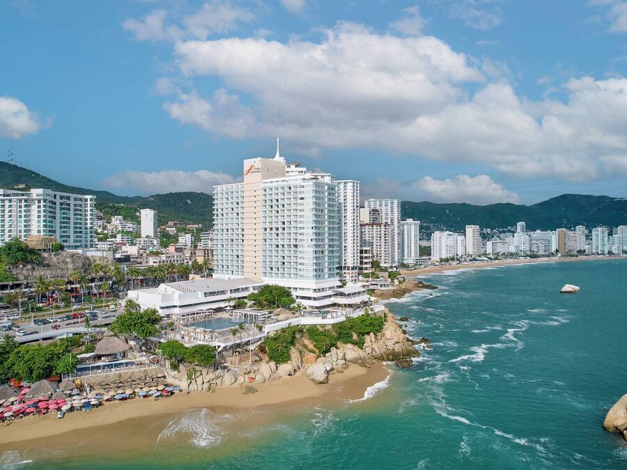 A coastal cityscape with high-rise hotels, a beach, and a rocky shoreline.