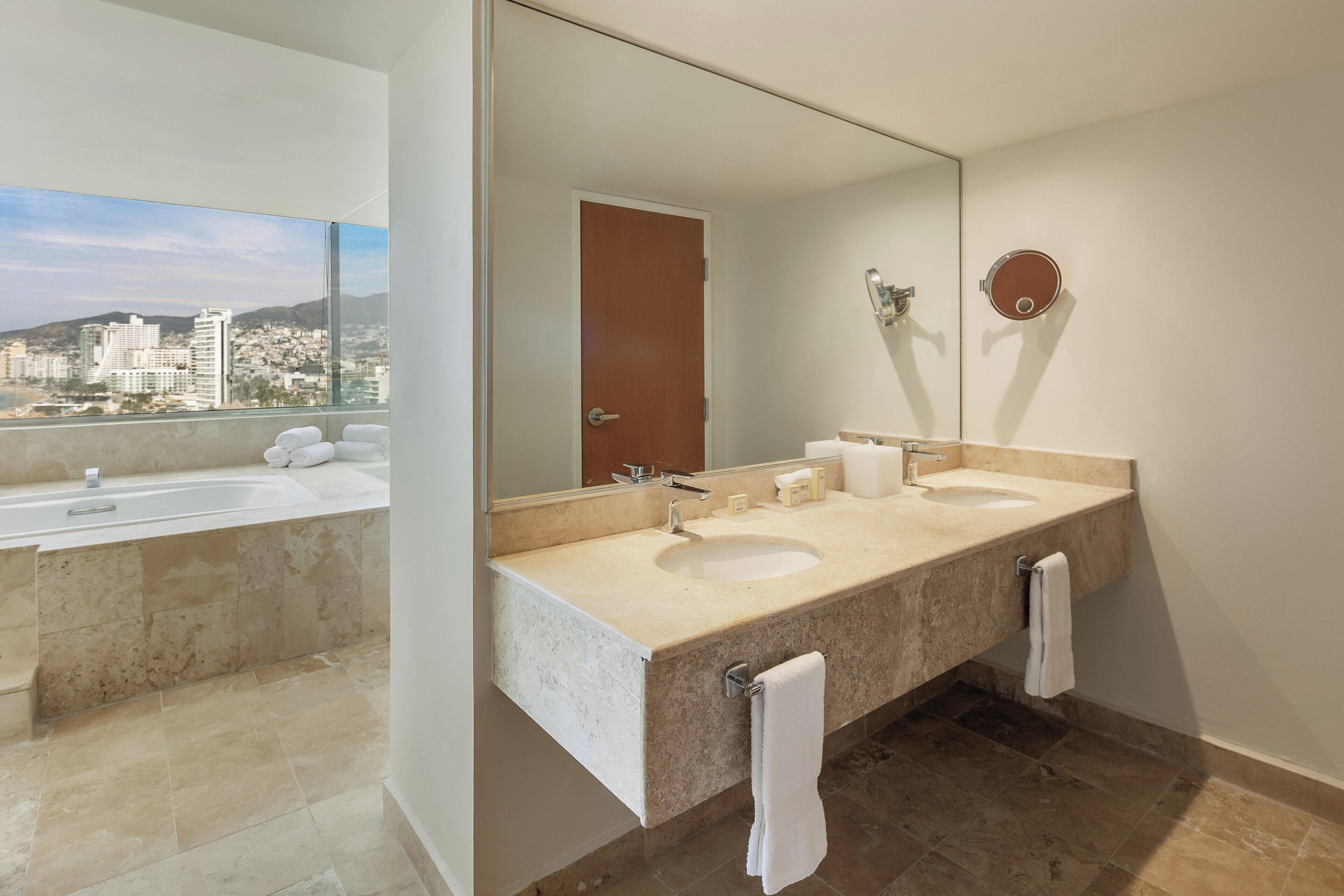 A modern bathroom with a dual sink vanity, a large mirror, and a bathtub.