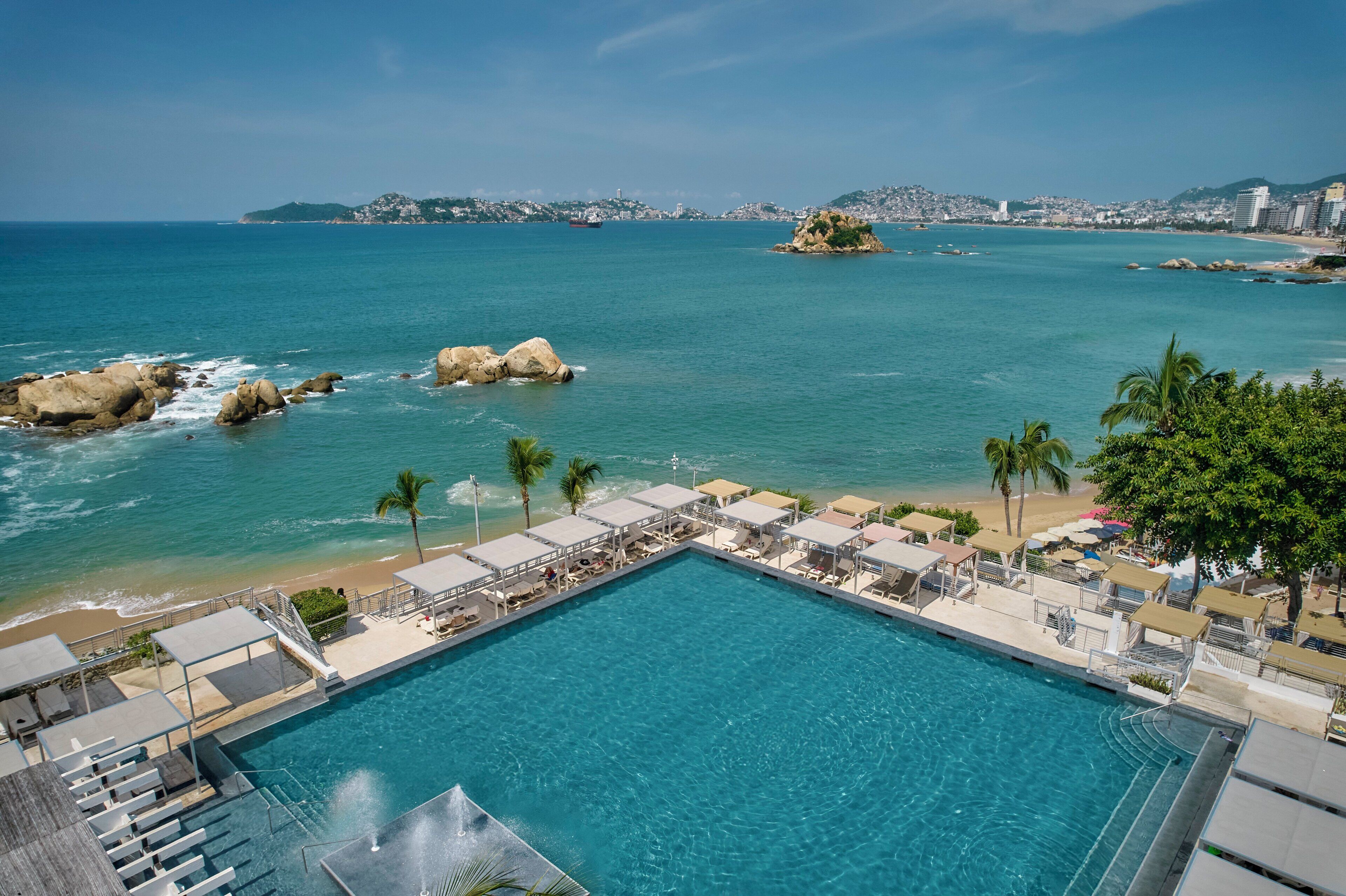 Una piscina al aire libre, camas de piscina con cargo, sombrillas